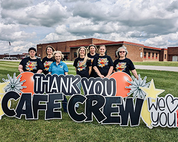 staff behind a sign that reads Thank you cafe crew