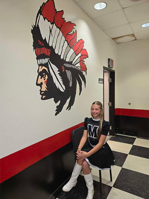 Cheerleader sitting in front of new mural