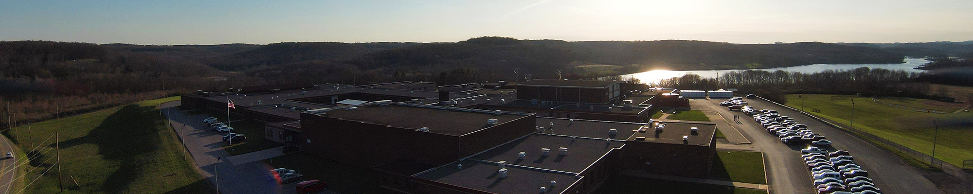 Students on the outside stairs next aerial view of sunset over campus