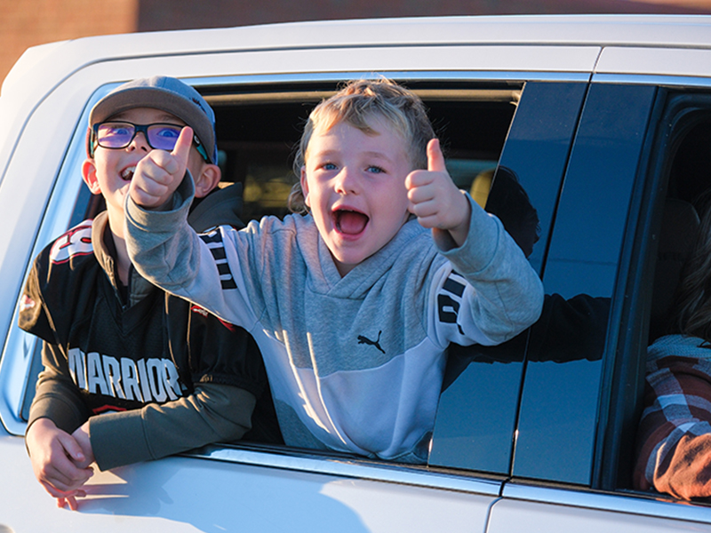 Student giving thumbs up from a car