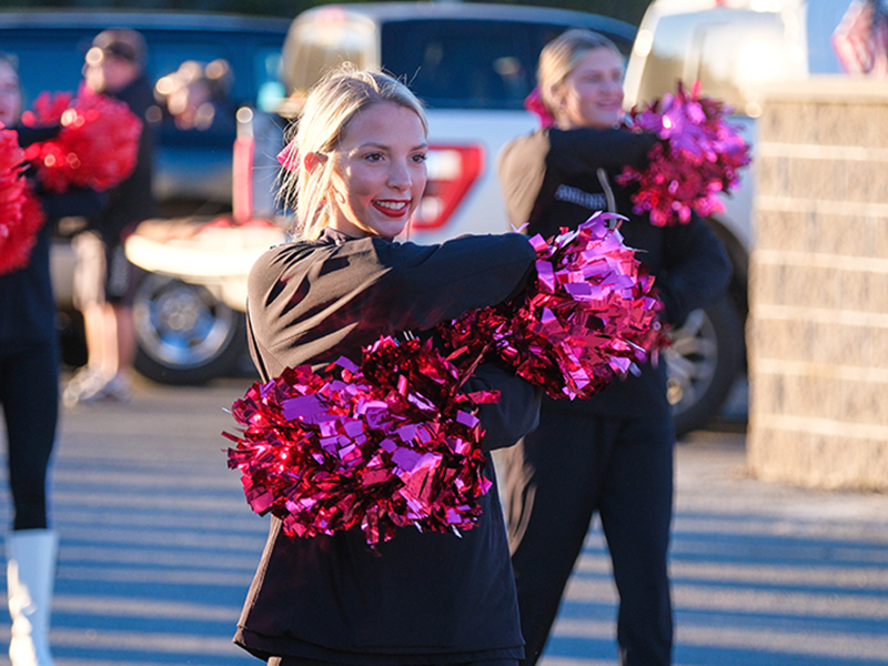 Cheerleader performing with pink pom-poms
