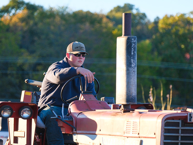 Student riding on a red tractor