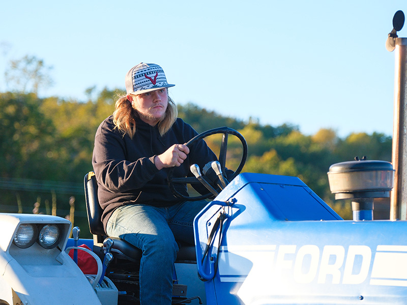 Student driving a blue tractor
